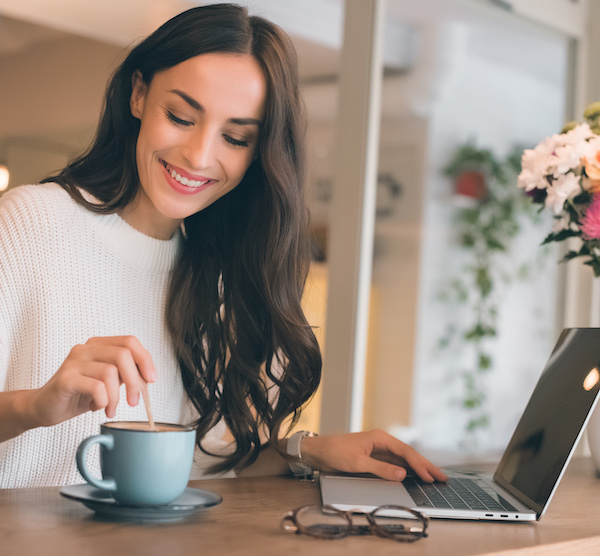 Woman buying wellness products from ecommerce store and drinking tea and smiling